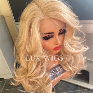 May include: A long, wavy, blonde wig with a lace front. The wig is styled in loose curls and has a natural-looking hairline.