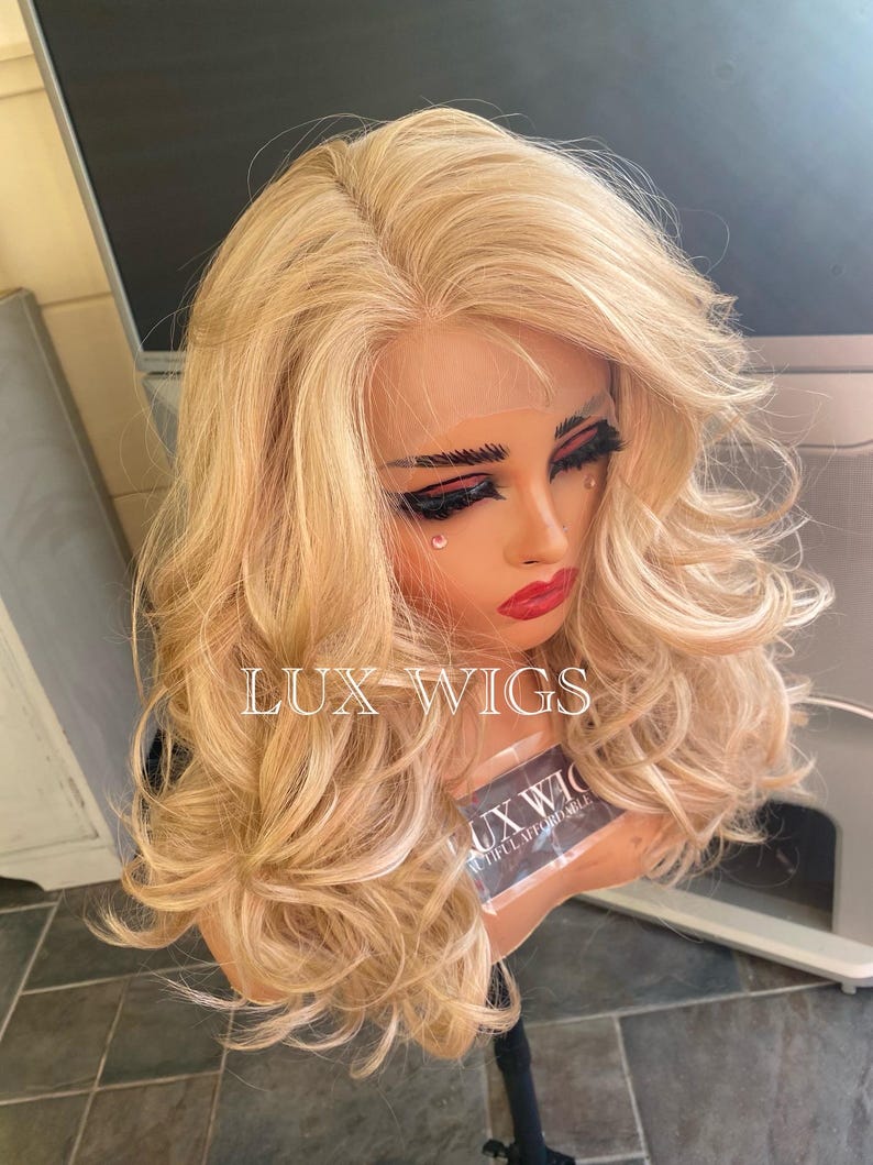 May include: A long, wavy, blonde wig with a lace front. The wig is styled in loose curls and has a natural-looking hairline.