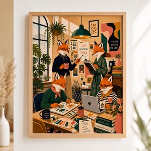 Op de afbeelding: Een ingelijste kunstdruk met vier antropomorfe vossen in een atelier. Eén vos schildert, één schrijft in een notitieboek, één werkt op een laptop en één houdt een mok vast. De scène bevat kunstbenodigdheden, boeken, planten en posters aan de muur.