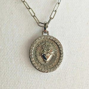 This minimalist necklace features a 18-inch silver-plated chain and a distinctive die-cast metal Sacred Heart Cross pendant. It's a versatile piece, suitable for boys, girls, men, or women. Other chain styles and lengths are available upon request.
