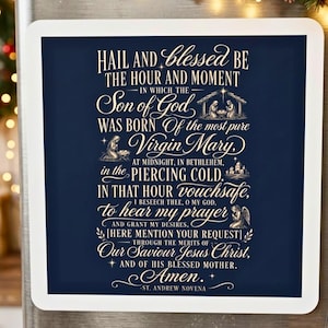 May include: A square magnet with a dark blue background and white text featuring the St. Andrew Novena prayer. The design includes small illustrations of a nativity scene, a kneeling figure, and an angel, all framed by a thick white border.
