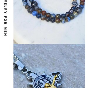 May include: A collection of beaded bracelets featuring various stone textures, including black lava, dalmatian jasper, and green agate, alongside a silver-toned crucifix pendant and a gold-toned crucifix with a Saint Benedict medal.