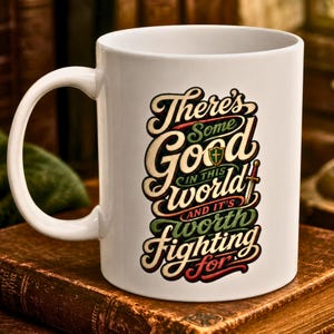 May include: A white ceramic mug featuring stylized, multi-colored typography that reads, "There's Some Good IN THIS world AND IT'S worth fighting FOR." The design includes a small green shield icon with a cross and a sword illustration.