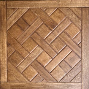 May include: A square wooden panel with a parquet pattern. The panel features a repeating herringbone design in various shades of brown. The outer edge is framed with a darker wood border, creating a defined edge.