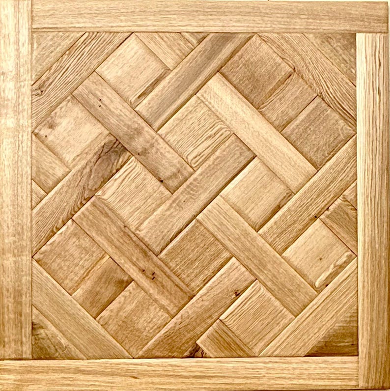 May include: Square wooden panel with a woven pattern. The panel features a light brown color with a natural wood grain texture. The design is framed by a border of the same wood.