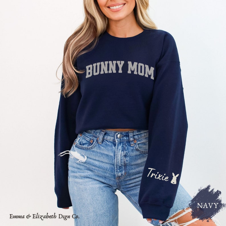 Peut inclure: Sweat-shirt bleu marine court avec le texte "Bunny Mom" en blanc et un graphique de lapin sur la manche. Le texte "Trixie" est &eacute;galement sur la manche.
