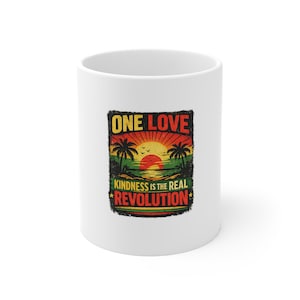 May include: White ceramic coffee mug with a colorful graphic. The design features a sunset over a beach with palm trees and the words "ONE LOVE" and "KINDNESS IS THE REAL REVOLUTION" in a distressed font.
