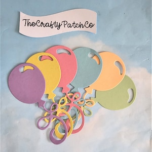 May include: A set of six die-cut paper balloons in various pastel colours, including purple, yellow, pink, blue, orange, and green. The balloons are attached to a set of five die-cut paper swirls in matching colours. The text "TheCraftyPatchCo" is visible in the background.