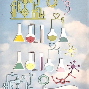 Könnte beinhalten: Eine Sammlung farbenfroher, wissenschaftlich gestalteter Stanzteile, darunter Bechergläser, Reagenzgläser und Molekularstrukturen. Die Stanzteile sind in Gelb-, Rosa-, Grün- und Lilatönen gehalten. The Crafty Patch Co. ist auf einem weißen Banner aufgedruckt.