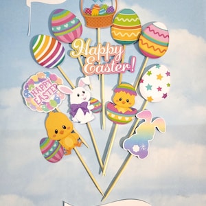 Puede incluir: Adornos para pasteles con temática de Pascua sobre palitos de madera. Los adornos incluyen huevos decorados, una cesta de huevos, pollitos y conejitos. Las palabras "Happy Easter!" y "Cake Toppers" también son visibles. El fondo es un cielo azul claro.