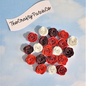 May include: A collection of 20 paper flowers in red, white, and burgundy. The flowers are arranged in a circular pattern on a light blue background.