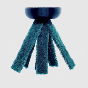 May include: A black plastic base with five green scrubbers attached to the top. The scrubbers are made of a textured material and are designed for cleaning.