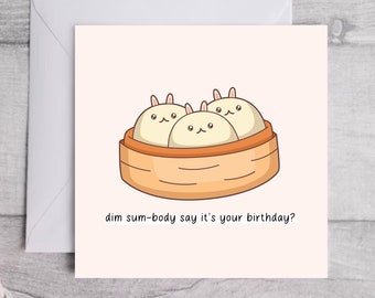 May include: A cute birthday card with a pun about dim sum. The card features a cartoon illustration of three steamed buns with bunny ears in a bamboo steamer. The text on the card reads "dim sum-body say it's your birthday?"