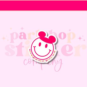May include: A white sticker with a smiling face and pink ears, resembling a popular cartoon character. The sticker has the text "most magical travel agent on earth" in a circular design around the face. The background is light pink with the words "party shop sticker company" in a faded design.
