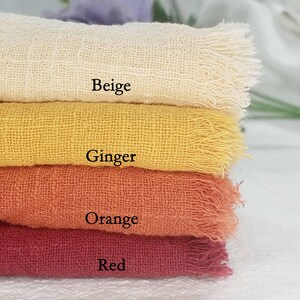 Könnte beinhalten: Ein Stapel von vier Stoffmustern in Beige, Ingwer, Orange und Rot. Jedes Muster hat einen ausgefransten Rand und eine gewebte Textur. Die Farben sind mit den entsprechenden Farbbezeichnungen versehen.
