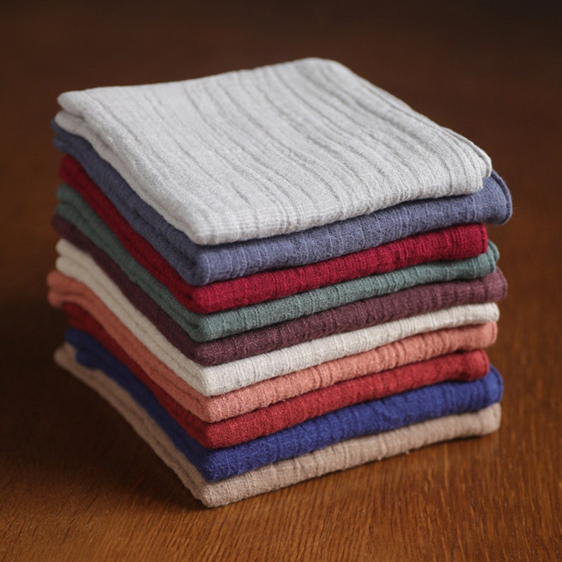 May include: A stack of 10 soft, textured fabric squares in various colors, including gray, blue, red, green, and beige. The fabric is folded neatly and arranged in a pyramid shape.