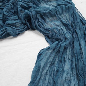 Könnte beinhalten: Ein blauer Stoff mit geknitterter Textur. Der Stoff ist über eine weiße Oberfläche gelegt.