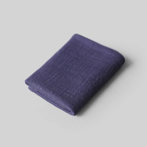 May include: A folded dark purple linen cloth. The cloth is soft and textured.