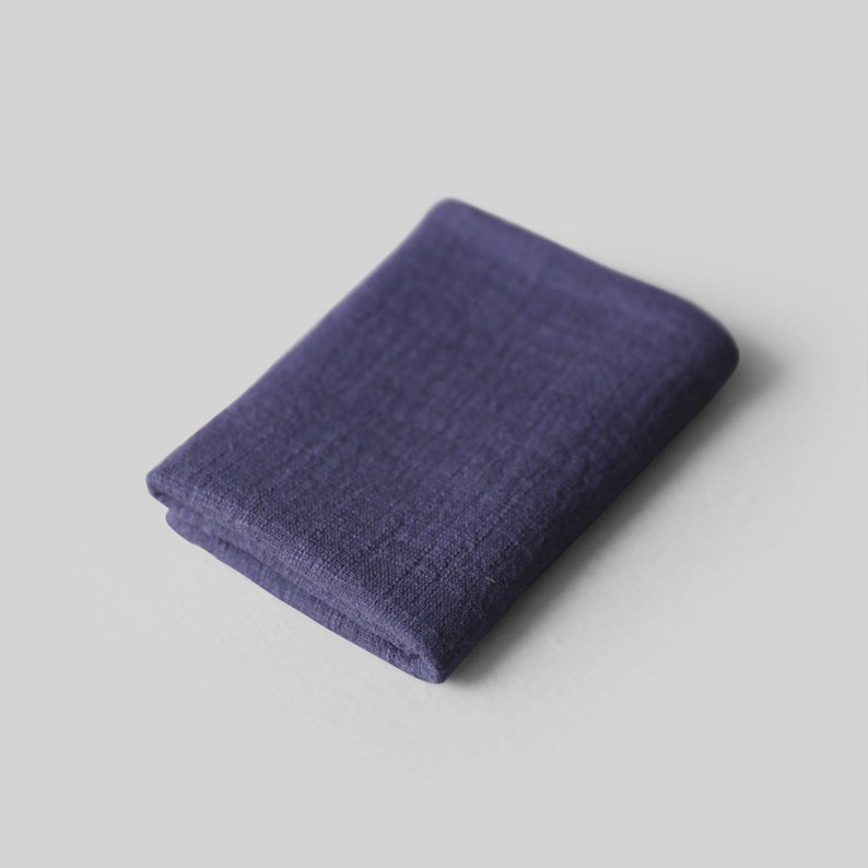 May include: A folded dark purple linen cloth. The cloth is soft and textured.