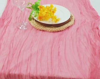 Könnte beinhalten: Ein rosa geknitterter Tischläufer mit einem weißen Teller, einem geflochtenen Untersetzer und einem Glas Wasser. Gelbe Blumen sind auf dem Teller arrangiert.