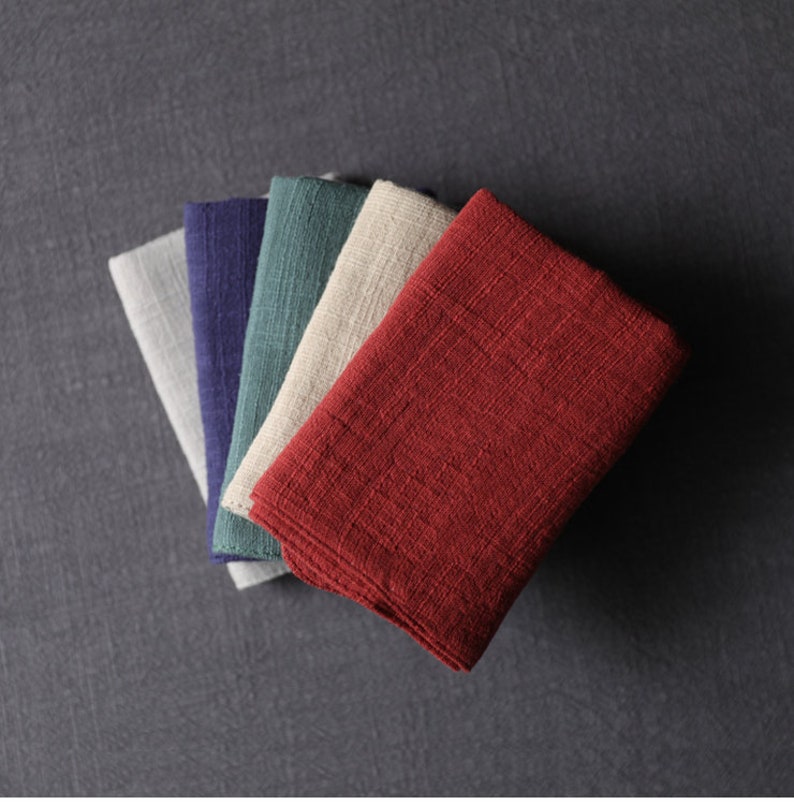 May include: Five folded fabric squares in different colors: gray, navy blue, teal, beige, and burgundy.