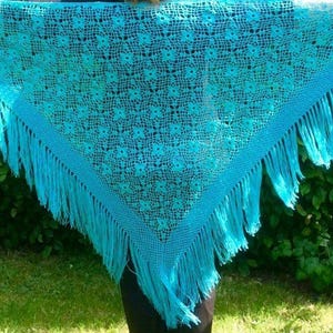 Peut inclure: Un châle en crochet bleu turquoise avec un motif floral délicat et une bordure à franges.
