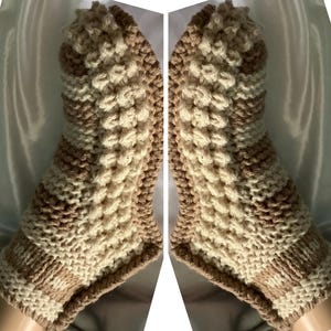 Puede incluir: Un par de calcetines de pantuflas de punto beige y marrón con un patrón texturizado.