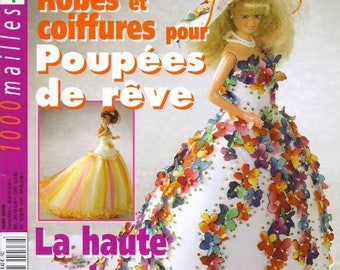 May include: A magazine cover titled 1000mailles featuring a doll wearing a white gown adorned with colorful fabric flowers and a matching wide-brimmed hat. The cover includes text in French and a smaller inset image of a doll in a yellow and white dress.
