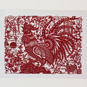 May include: Red paper cut-out art depicting a rooster with intricate details. The rooster is surrounded by flowers, clouds, and bamboo.