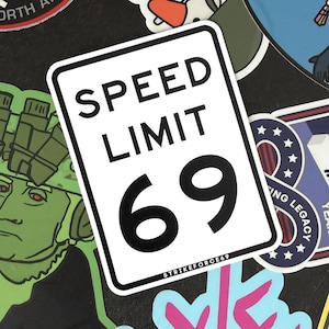 Puede incluir: Una pegatina rectangular blanca con borde negro que presenta el texto SPEED LIMIT y el número 69 en una fuente negra grande. En la parte inferior de la pegatina, el texto STRIKEFORCE69 está impreso en una fuente negra más pequeña sobre fondo blanco.