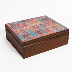 May include: A wooden box with a hinged lid. The lid is decorated with a colorful print of a cityscape. The box is a dark brown color.
