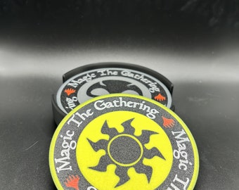 May include: A yellow and black Magic: The Gathering coaster with a black sunburst design and the words "Magic The Gathering" written around the edge.