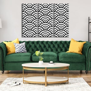 Może przedstawiać: Zielona welurowa sofa z pikowaniem i złotymi gwoździami ozdobnymi. Sofa ma dwa ż&oacute;łte poduszki i jedną poduszkę w szaro-białe wzory. Sofa stoi przed białą ścianą, nad kt&oacute;rą wisi czarno-biały geometryczny wydruk.