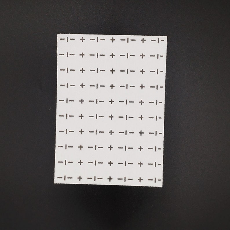 Rectangular sashiko design of crosses and dashes on a black background.