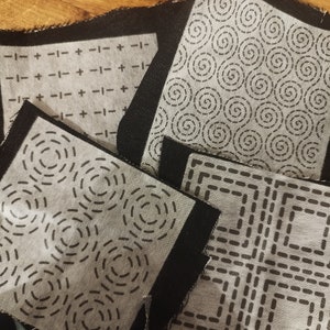 Sashiko transfers attached to fabric samples. Two square designs and two rectangular design patches