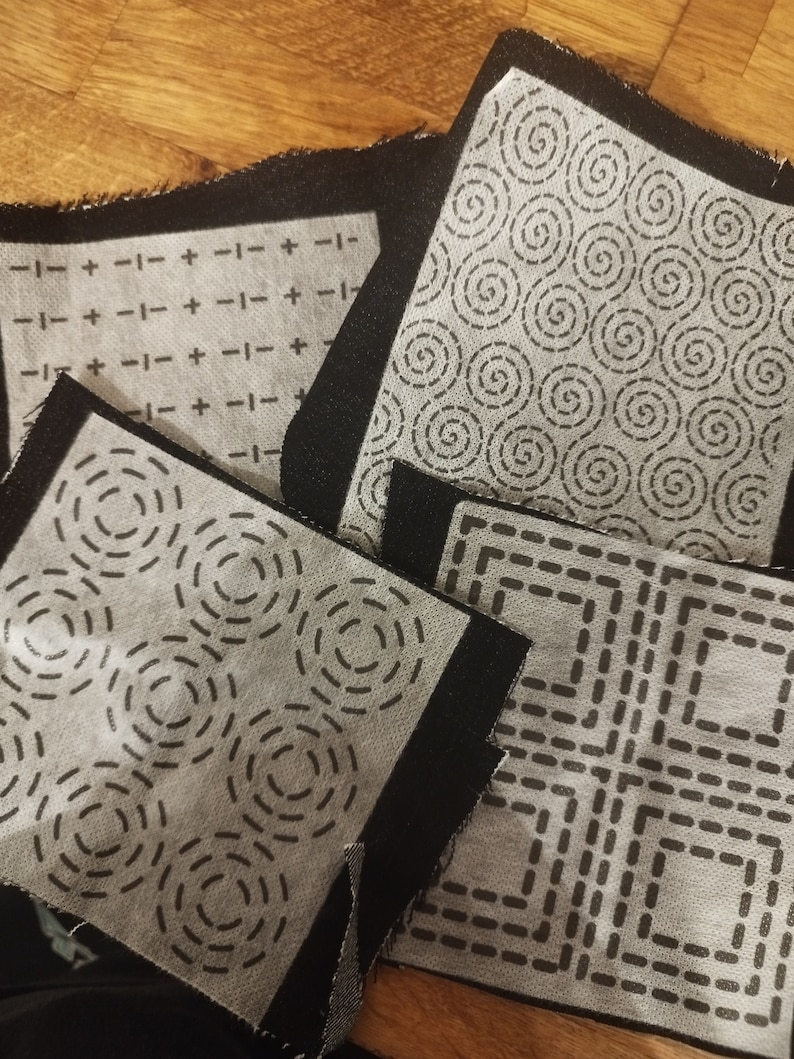 Sashiko transfers attached to fabric samples. Two square designs and two rectangular design patches