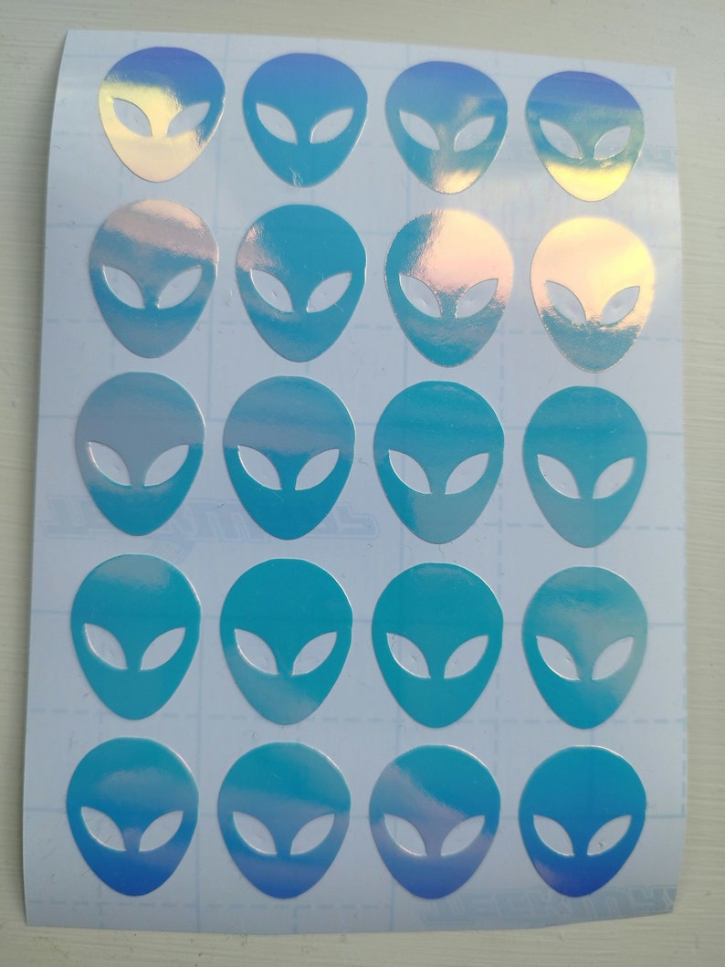 May include: A sheet of 18 iridescent blue alien head stickers. The stickers are arranged in a grid pattern on a white sheet.