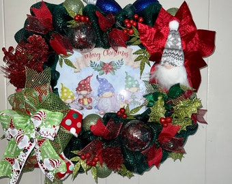 May include: A Christmas wreath with a green base, red and green ribbon, red poinsettias, and a sign that says "Merry Christmas". There are four gnomes on the sign, and a single gnome is on the wreath.
