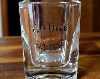 May include: A clear glass shot glass with the words "Jack Daniel's Whiskey" printed on the front.