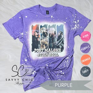 May include: Purple t-shirt with a graphic featuring Post Malone with Jelly Roll. The design is in a white square, with a distressed, bleached effect. The shirt has white paint splatters and the text "SAVVY CHIC Shoppe".