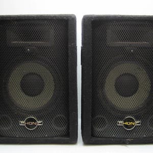 May include: Two black speaker cabinets with a black speaker grille and a white speaker cone. The speakers have a gold logo that says "Phonic".