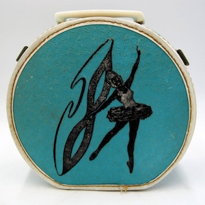 May include: A vintage turquoise blue hard-sided round case with a white handle and a black silhouette of a ballerina with a ribbon. The case has a white trim around the edge.
