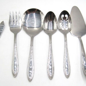 May include: Set of eight stainless steel kitchen utensils with ornate handles. The set includes a serving spoon, a slotted spoon, a spatula, a ladle, a butter knife, a fork, and a sugar spoon.