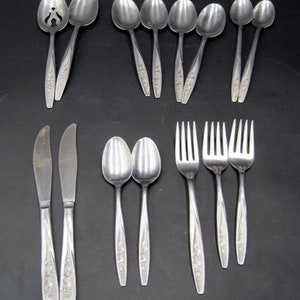 May include: A set of silverware with a floral design. The set includes knives, forks, spoons, and a serving spoon.