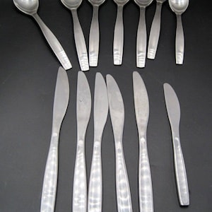 May include: A set of silver flatware, including spoons and knives. The flatware has a textured design and a modern style.