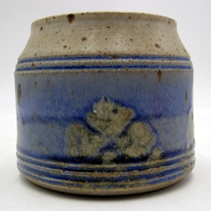 May include: A small, blue and white ceramic jar with a textured surface and a floral design. The jar has a wide mouth and a rounded bottom.