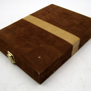 May include: A brown suede box with a tan leather trim. The box has a gold latch.