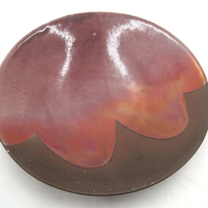May include: A ceramic dish with a brown and pink glaze. The dish has a wavy edge and is oval shaped.