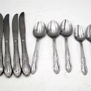 Peut inclure: Un ensemble de couverts en acier inoxydable avec des manches ornés, comprenant des couteaux, des cuillères et une fourchette.