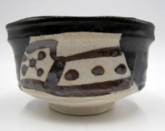May include: A black and white ceramic bowl with a brown and gray abstract design. The bowl has a rounded shape and a wide rim.